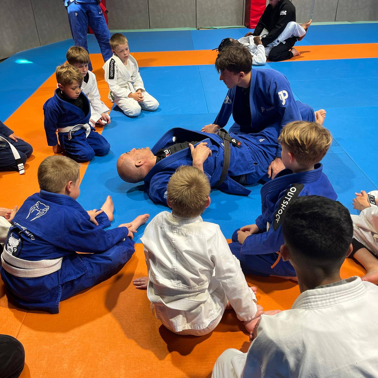 Coach corrigeant la posture d’un enfant pendant un cours de JJB